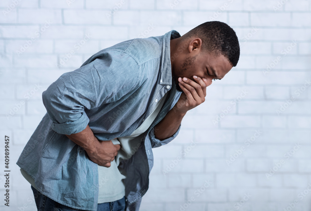 African Man Vomiting Having Nausea And Stomachache, Gray Background, Side-View African Man Vomiting Having Nausea And Stomachache, Gray Background, Side-View