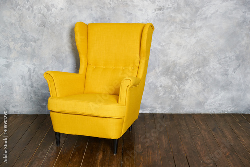 The yellow textile chair stands on a dark brown wooden floor