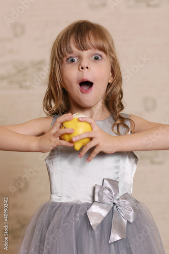 little blond baby girl eating sore lemon and grimacing on retro wall interior background