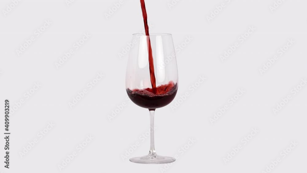 Red wine pouring into wine glass in white studio, close up slow motion Red wine pouring into wine glass in white studio, close up slow motion