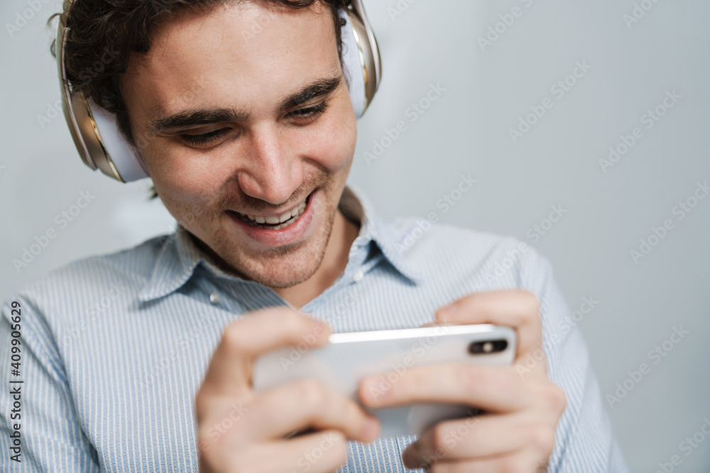 Caucasian businessman in headphones using cellphone in office Caucasian businessman in headphones using cellphone in office