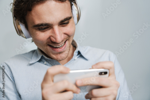 Caucasian businessman in headphones using cellphone in office