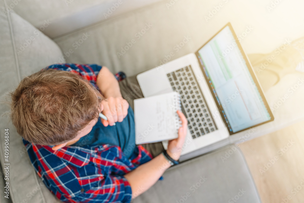 Top view of a young male programmer drinking coffee and writing on a laptop keyboard. The concept of people working with technology and computer at home Top view of a young male programmer drinking coffee and writing on a laptop keyboard. The concept of people working with technology and computer at home