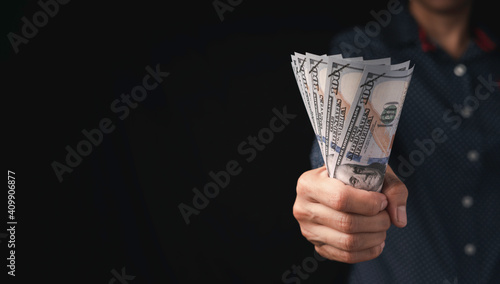 Businessman holding US dollar money in hand on black background. USD bills in the concept of investment, financial, and successful in business.