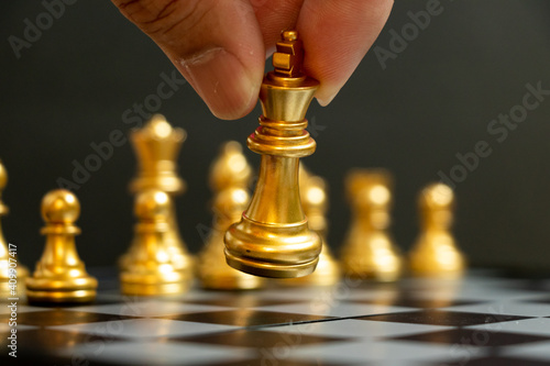 Business man hold king to move in chess game on black background (Concept for company strategy, vision or decision)