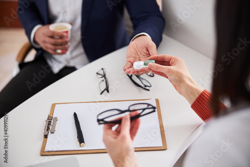 Optician offering corrective lenses and a pair of spectacles