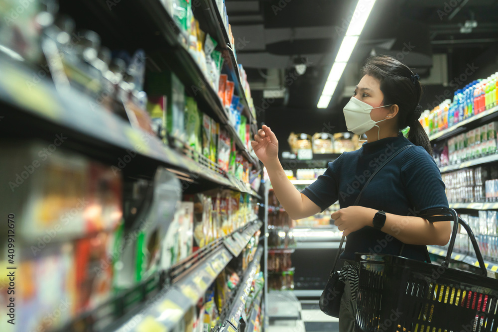 new normal after covid epidemic young smart asian female shopping new lifestyle in supermarket with face shild or mask protection hand choose consumer products new normal lifestyle