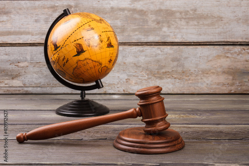 Obraz na plátně Brown globe with gavel on wood. International court concept.