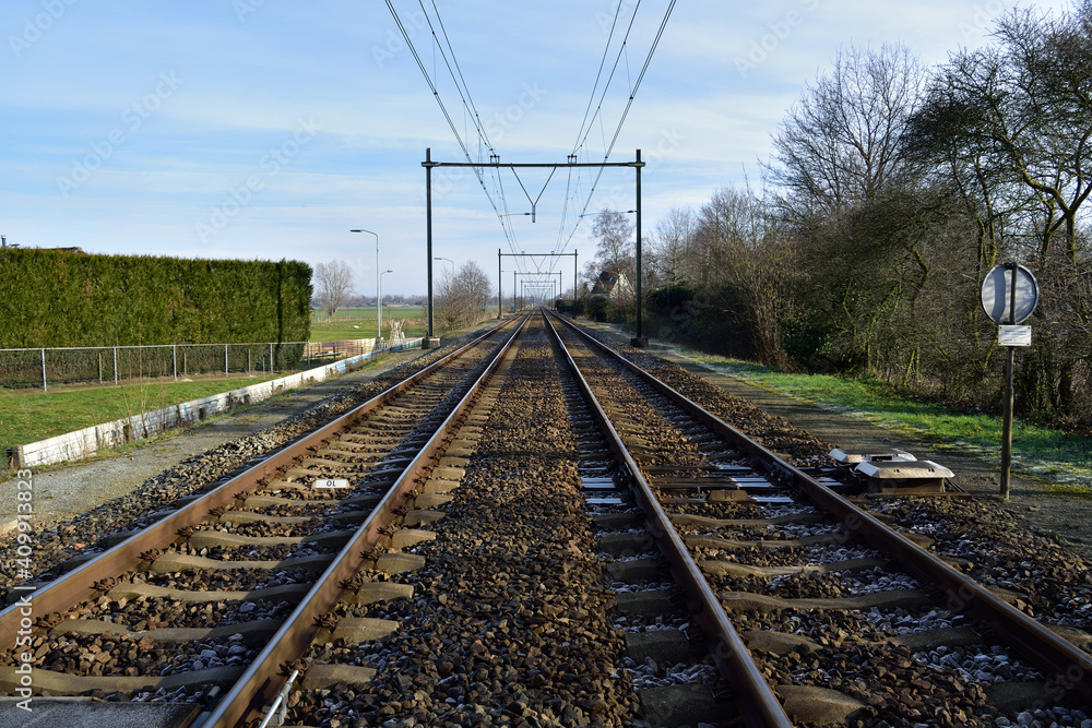 Railroad tracks in the Netherlands countryside fading into a diminishing perspective in the far distance
