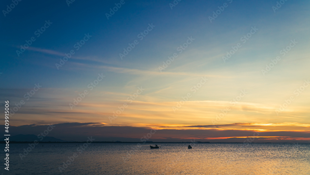 Dusk sky over sea and minimal fishing boat in the evening on twilight with colorful sunlight
