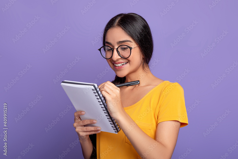 Woman holding pen writing in notebook at studio Woman holding pen writing in notebook at studio
