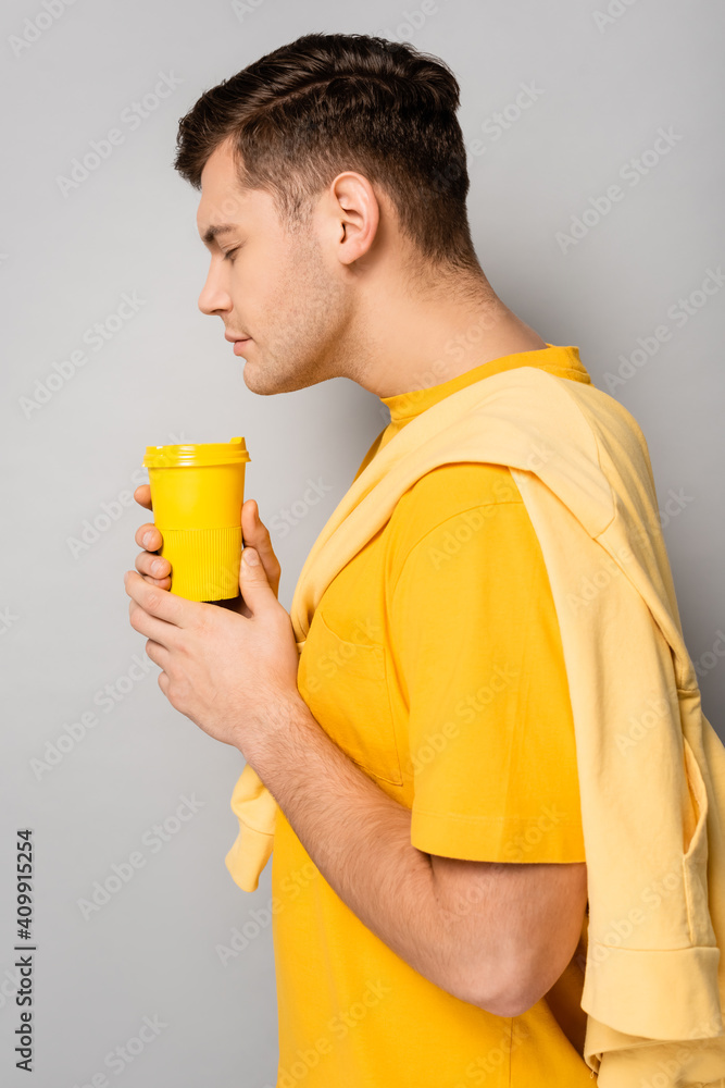 Side view of man smelling takeaway coffee on grey background Side view of man smelling takeaway coffee on grey background