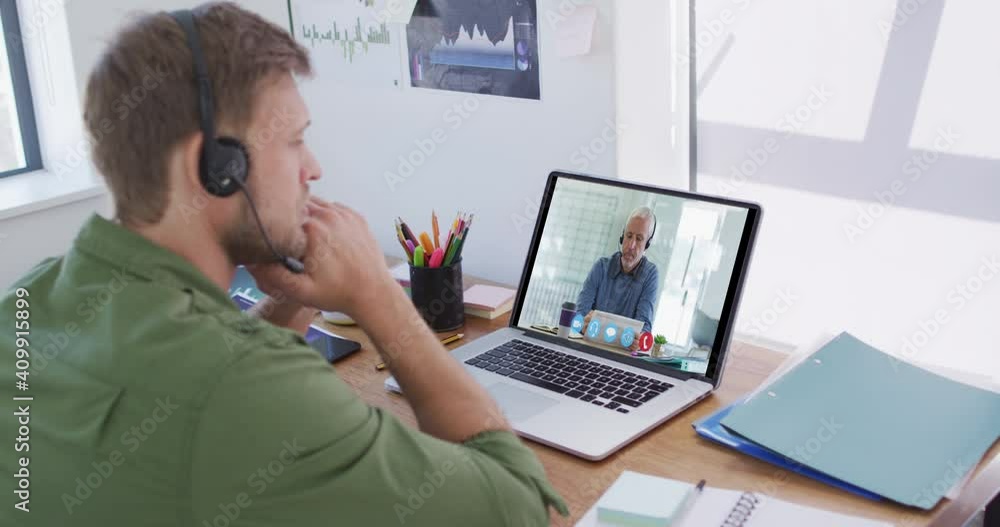 Caucasian man using laptop and phone headset on video call with male colleague Caucasian man using laptop and phone headset on video call with male colleague