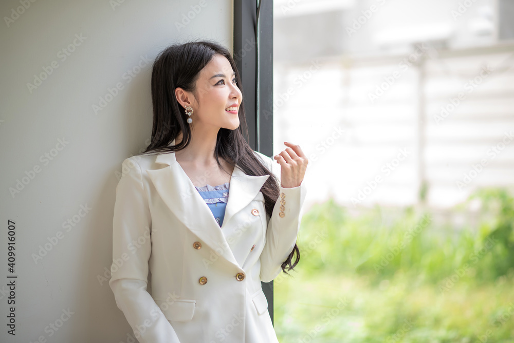 Image of business woman smiling face asian standing at the window at the office.