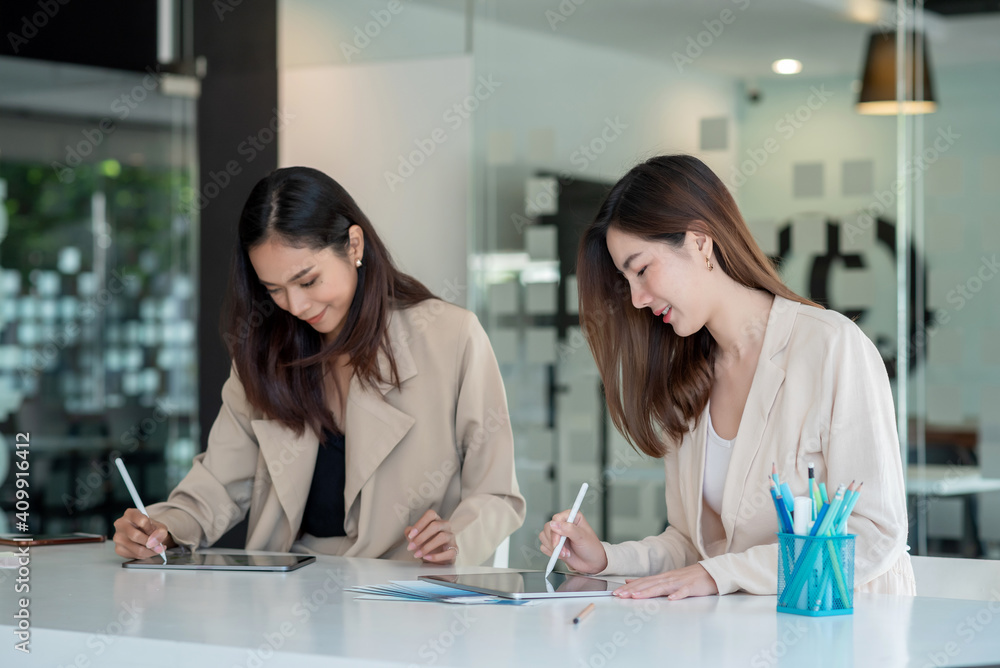 Two young asian businesswoman help to analyze the working using a tablet at the office. Two young asian businesswoman help to analyze the working using a tablet at the office.