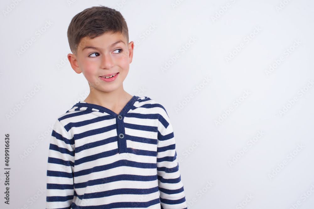 Oops! Portrait of little cute boy kid wearing red stripped t-shirt against white wall clenches teeth and looks confusedly aside, realizes her bad mistake, Oops! Portrait of little cute boy kid wearing red stripped t-shirt against white wall clenches teeth and looks confusedly aside, realizes her bad mistake,