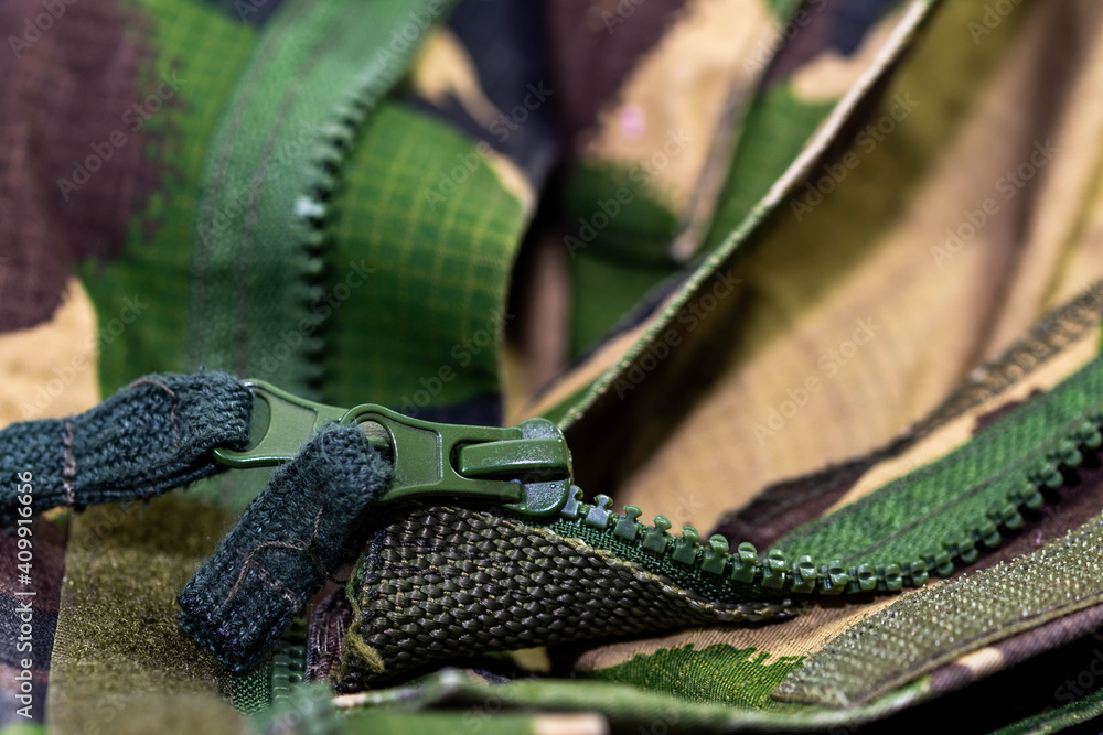 Fototapeta premium Green zipper on military clothes close up macro shot, space for text.