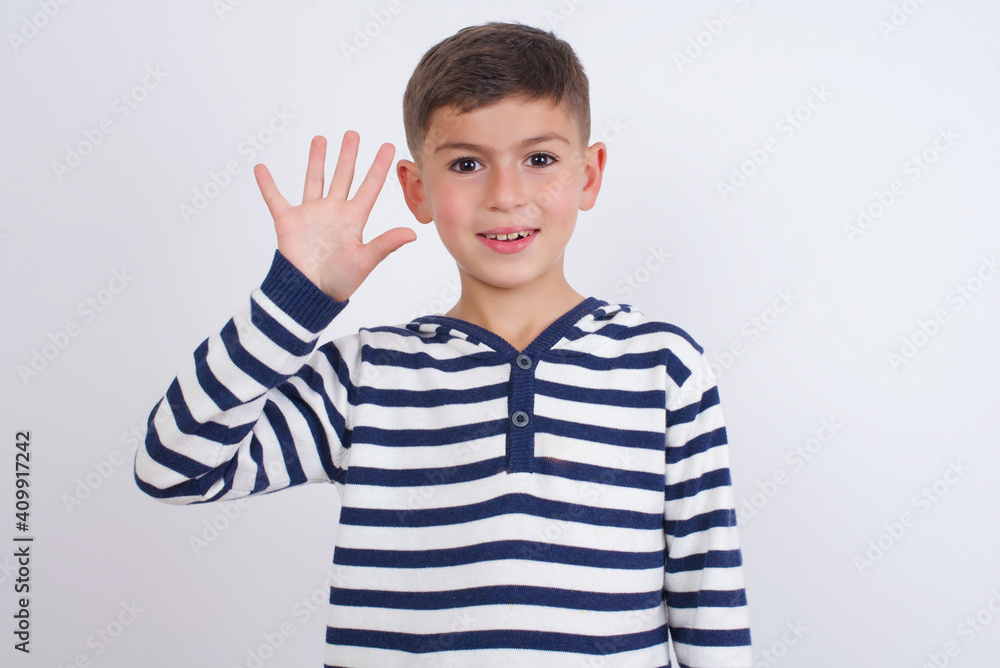little cute boy kid wearing red stripped t-shirt against white wall showing and pointing up with fingers number five while smiling confident and happy. little cute boy kid wearing red stripped t-shirt against white wall showing and pointing up with fingers number five while smiling confident and happy.