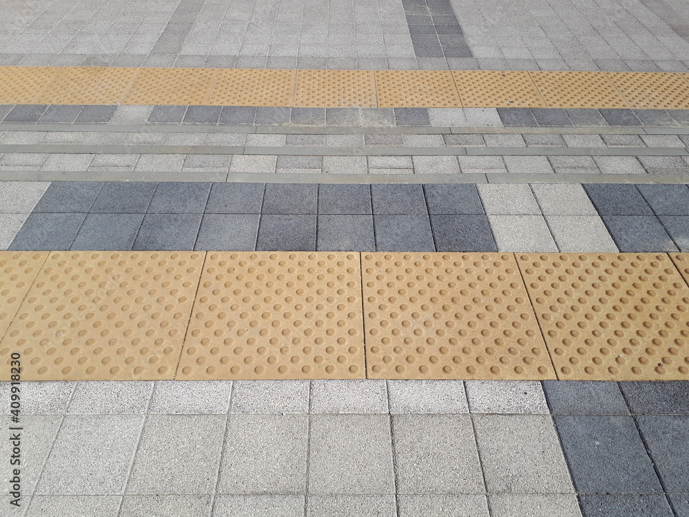 Grey paving slabs with yellow anti-slip inserts.