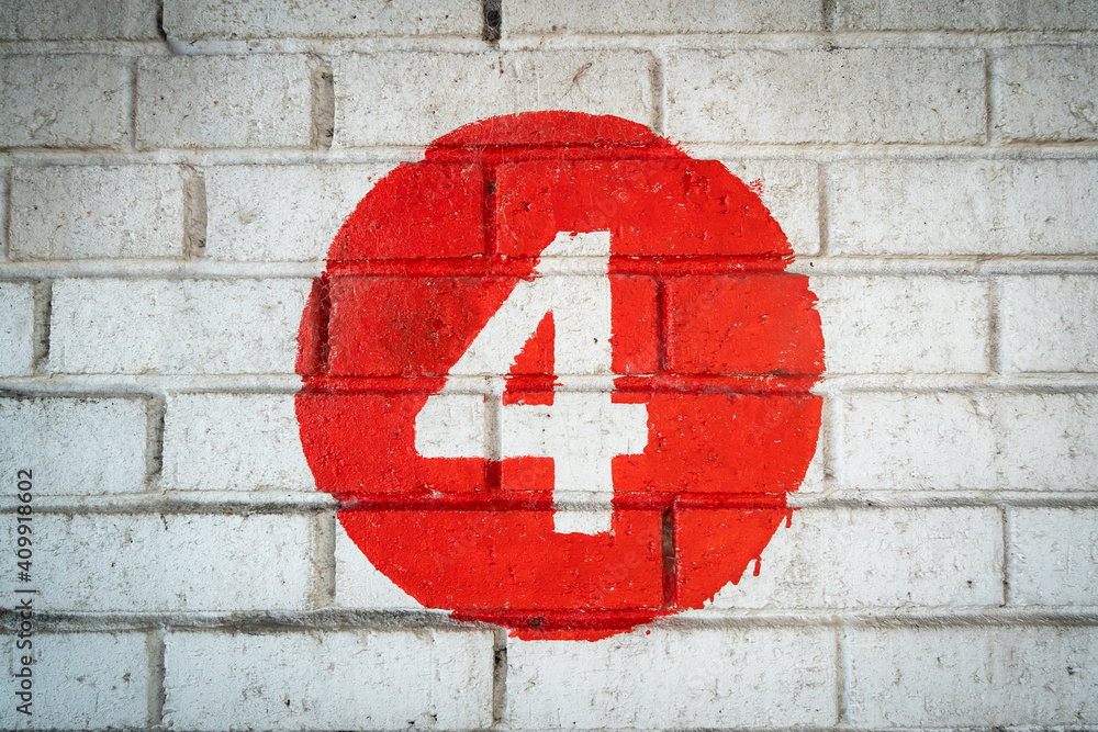 White coloured hand painted level number four in the middle of a red circle painted on an old textured brick wall with runs in the colour White coloured hand painted level number four in the middle of a red circle painted on an old textured brick wall with runs in the colour