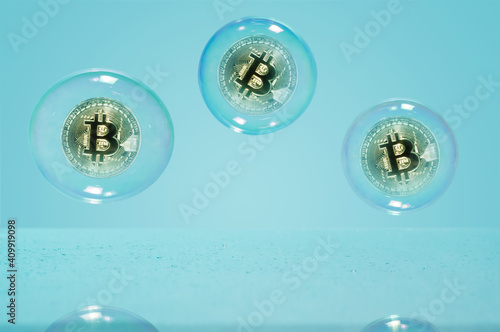 Bitcoin in a soap bubble on blue background. Concept of risks and dangers of investing to bitcoin. © svetazi