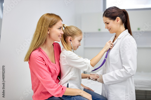 Wallpaper Mural girl playing with stethoscope in hospital, have fun with doctor woman in medical suit, listen to heartbeat of nurse. medicine, healthcare concept Torontodigital.ca