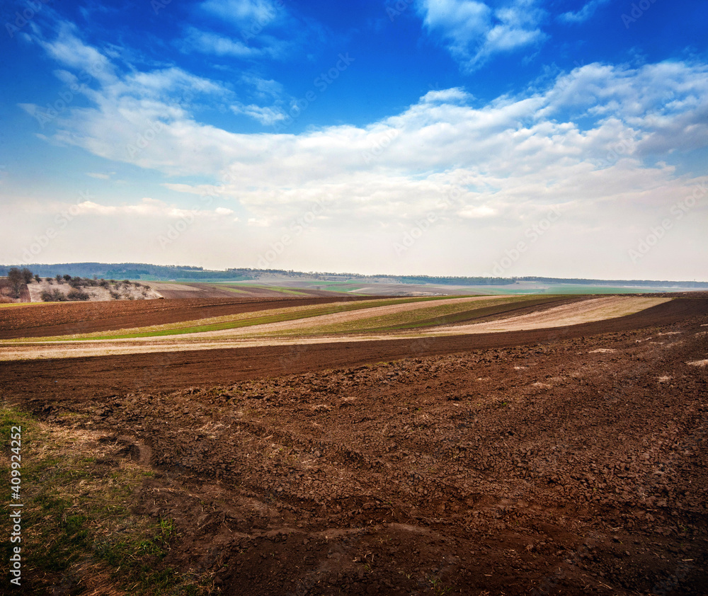 Fototapeta premium spring field, plowed soil and hills landscape in the background