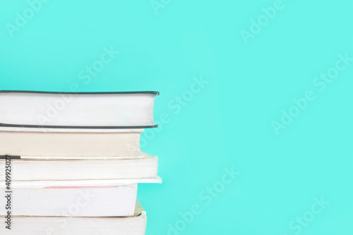 stack of text books on green pastel background , minimal style