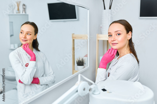 Portrait young beautiful cosmetologist in cosmetology cabinet. Beautiful caucasian woman on a cosmetology procedure. Wellness center. Healthcare, clinic, cosmetology photo