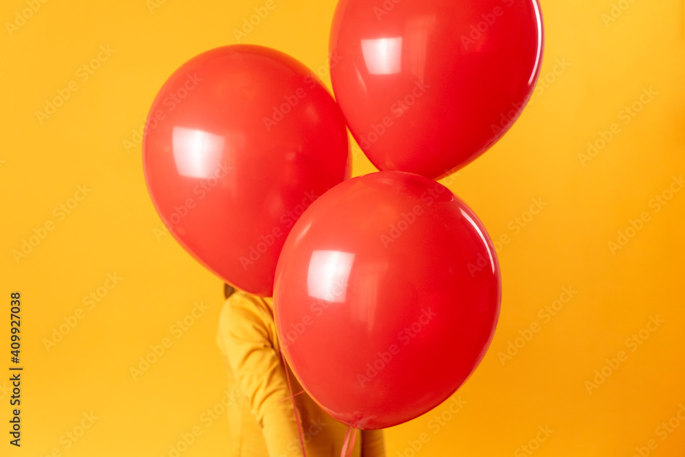 The kid plays on a yellow background with red balloons. Boy holds balls, concept of fun and happiness, love