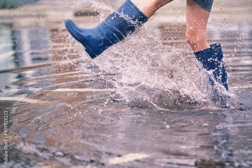 Canvas Print Female legs in rubber boots in a huge puddle scatter splashes