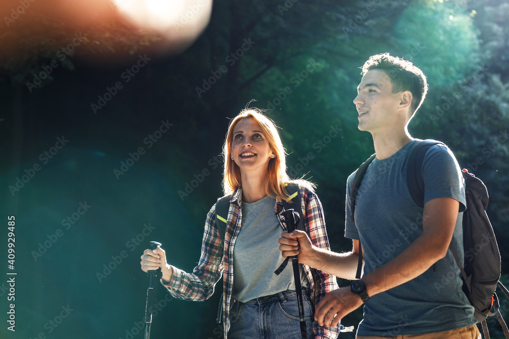 Young couple hiking in nature.They walking trough forest on beautiful sunset.	
