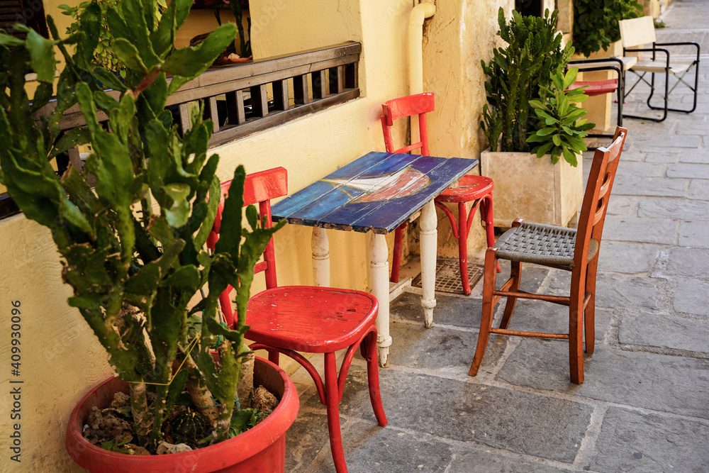 Fototapeta premium a small wooden table and chair in an alley in greece