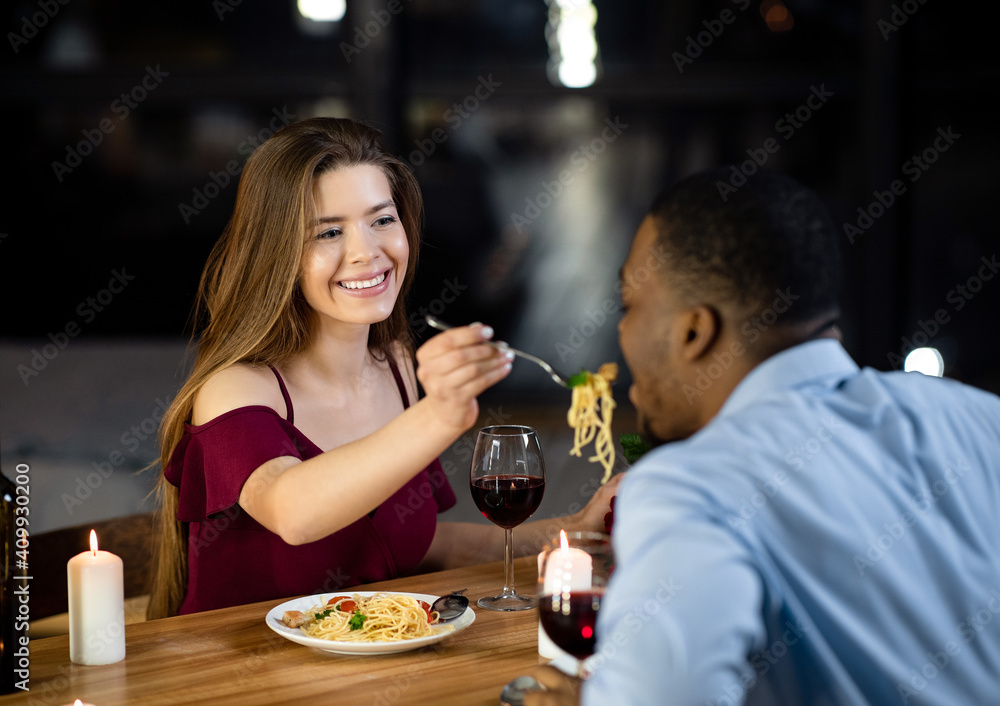 Loving Woman Feeding Her Black Boyfriend With Spaghetti During Dinner In Restaurant