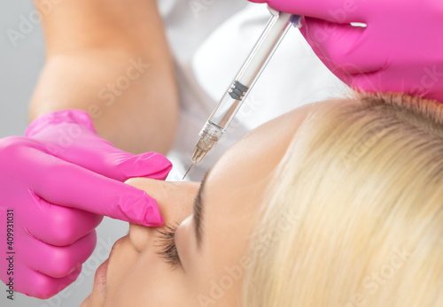 Canvas Print The doctor does injections to correct the hump on the nose with the beauty of the blonde