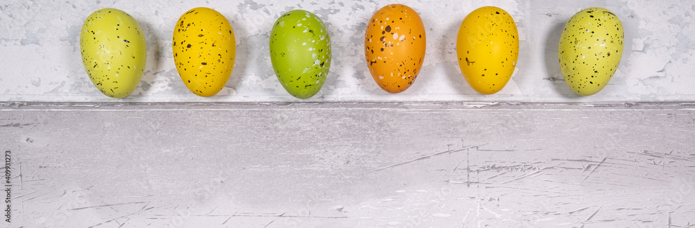 green and orange yellow easter eggs on a background of old wooden boards resembling old parquet. Easter concept