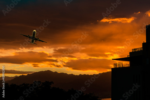 Landing airplane above colorful clouds, mountains and buildings of a city, Mi...