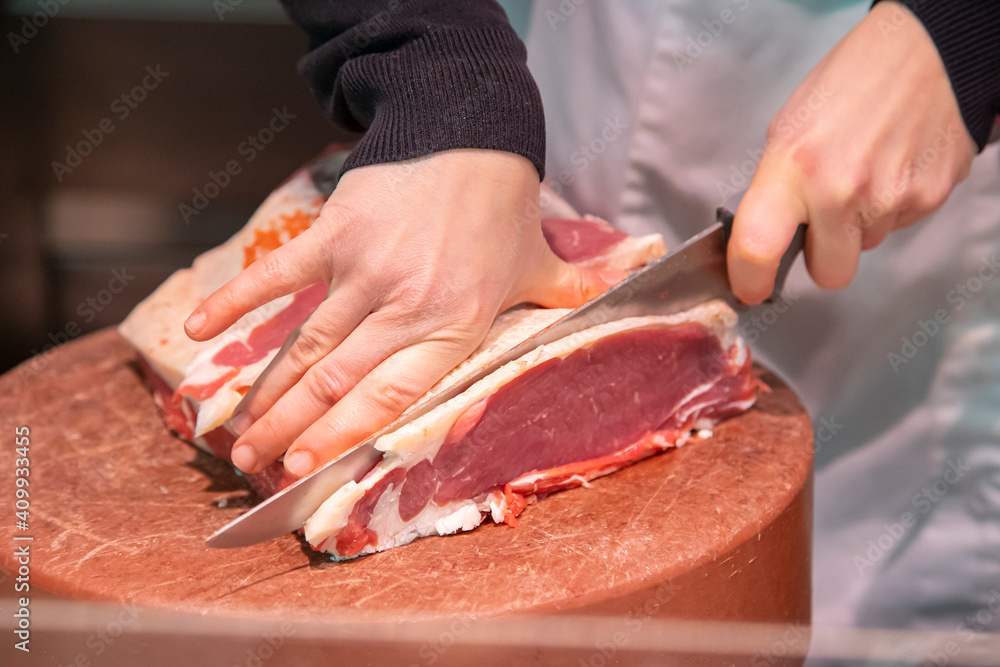 Butcher cutting meat with a knife.