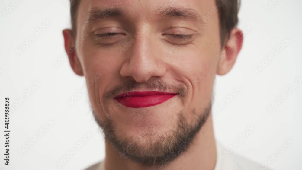 Close up portrait beautiful shy bearded male, look at camera isolated on white wall background. Pretty Caucasian man wear red lipstick on lips, smile, flirt. Romantic concept for Happy Valentine’s day Close up portrait beautiful shy bearded male, look at camera isolated on white wall background. Pretty Caucasian man wear red lipstick on lips, smile, flirt. Romantic concept for Happy Valentine’s day