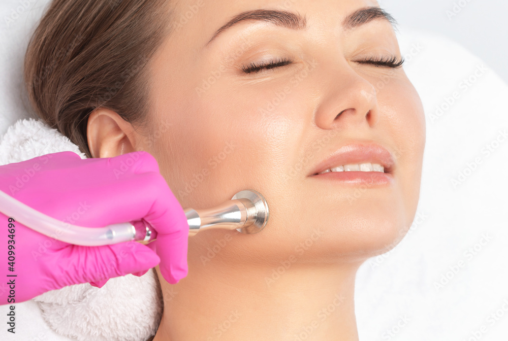 Cosmetologist makes procedure microdermabrasion on the face against acne and blackheads near the eyes. Women's cosmetology in the beauty salon. Cosmetologist makes procedure microdermabrasion on the face against acne and blackheads near the eyes. Women's cosmetology in the beauty salon.