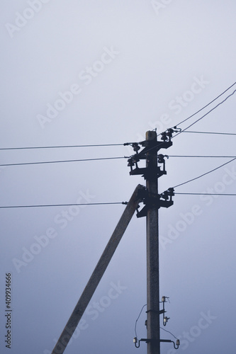 Electric pillar with wires in dark overcast sky.