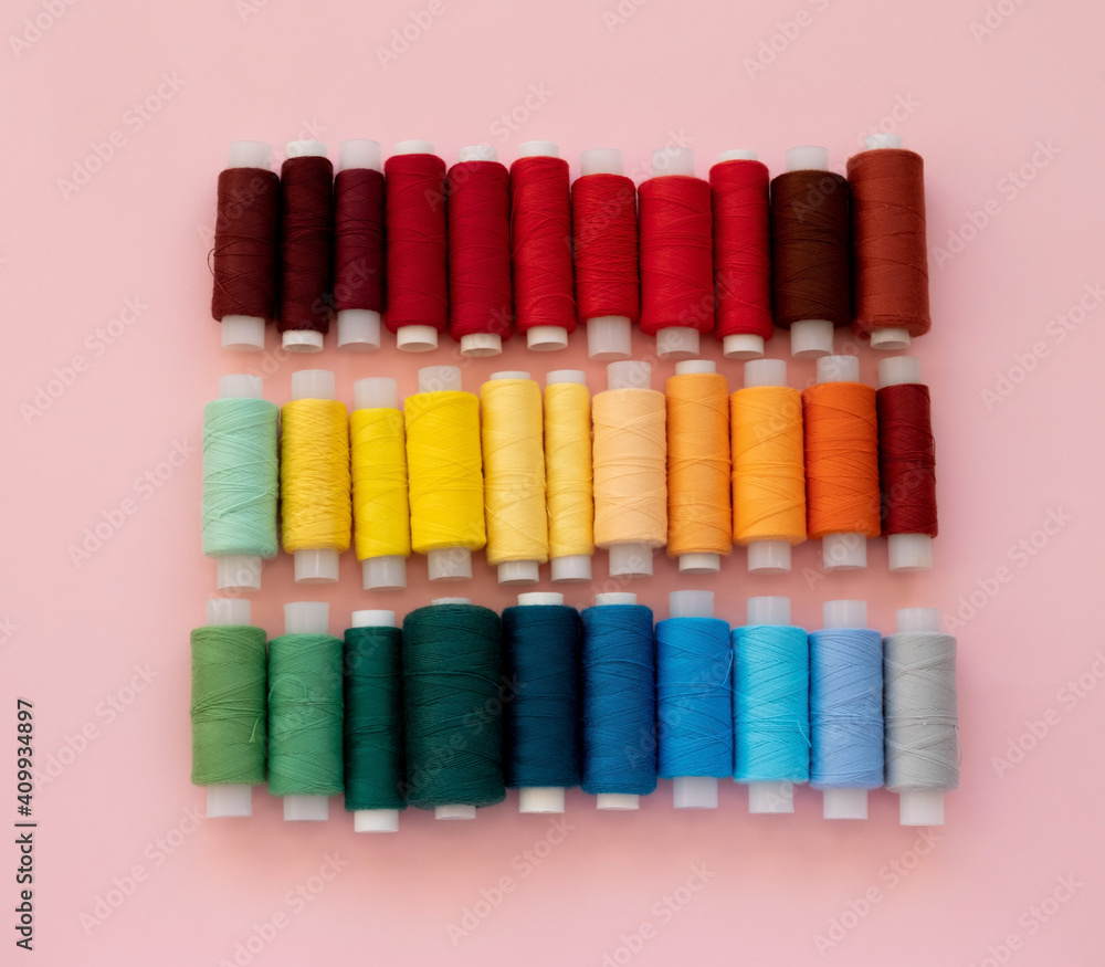Collection of colored thread layout on a pink background. Handmade and sewing minimal concept. Collection of colored thread layout on a pink background. Handmade and sewing minimal concept.