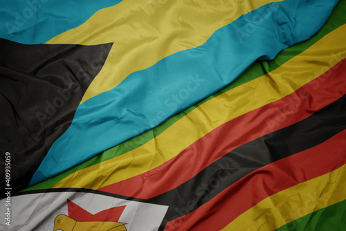 waving colorful flag of zimbabwe and national flag of bahamas.