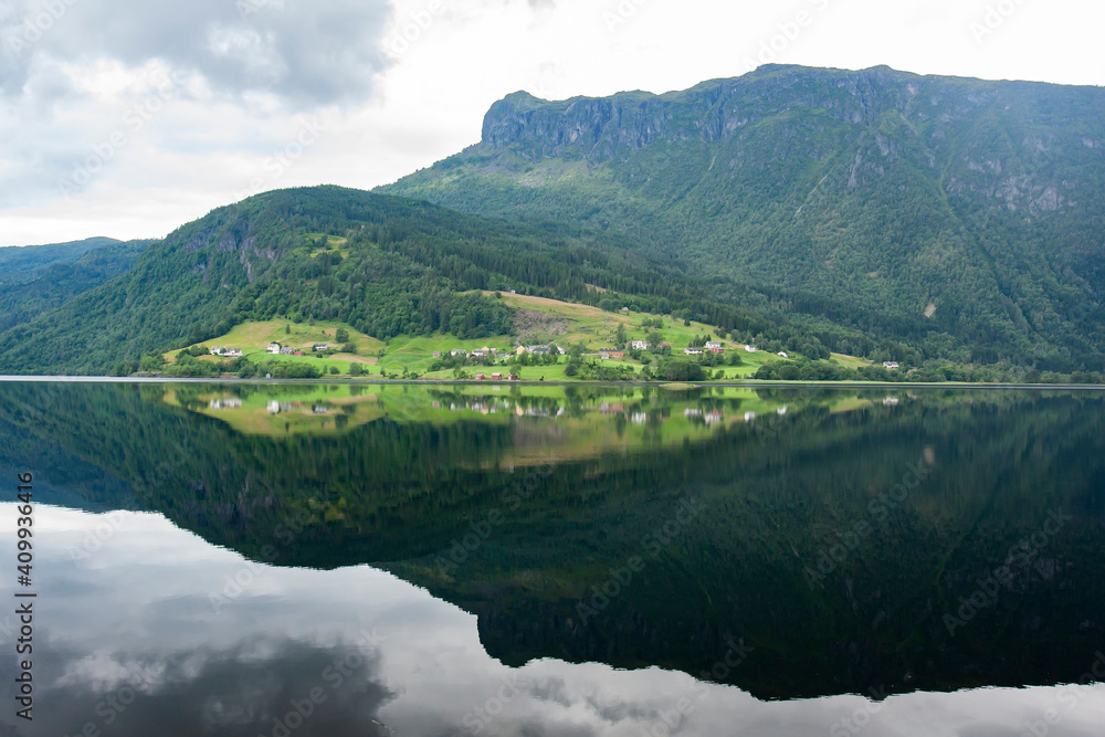 Beautiful reflection of the hillside on fjord water surface in Norwegian countryside
