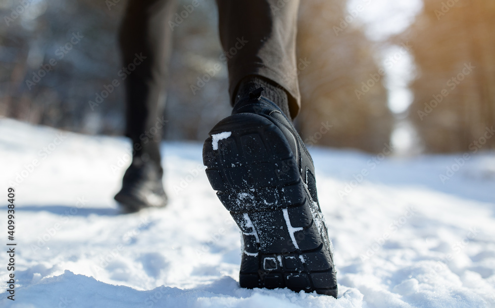 Cropped view of sportsman jogging on snowy road in winter, closeup of feet in sneakers, copy space. Outdoor activities Cropped view of sportsman jogging on snowy road in winter, closeup of feet in sneakers, copy space. Outdoor activities