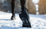 Cropped view of sportsman jogging on snowy road in winter, closeup of feet in sneakers, copy space. Outdoor activities