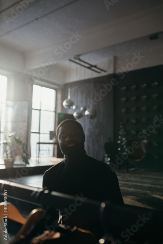 Photo of a man in an apartment standing against the background of a window from which the sun glare is visible © DmitryStock