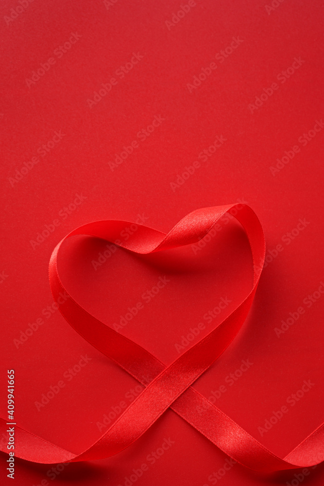 Red ribbon with heart shape on red background. Valentines day Or Love background concept. 