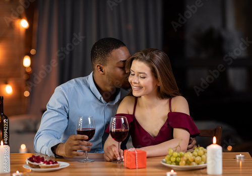 Multiracial couple dating and drinking wine during romantic dinner in restaurant