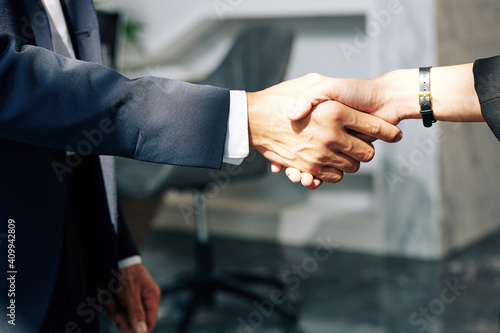 Close-up image of businessman and businesswoman shaking hands after successful meeting